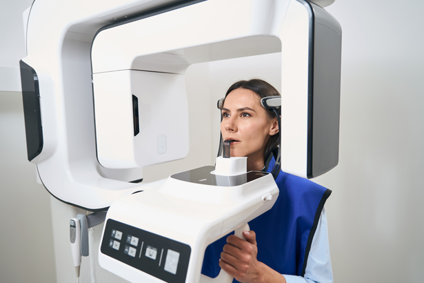 Dental professional operating cone beam CT scanner for endodontic imaging in clinical setting.