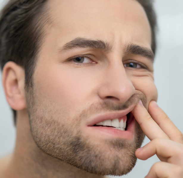 Man examining or pointing to his mouth and teeth, suggesting dental concern or oral health issue.